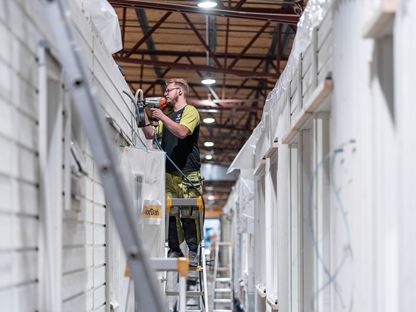 Fabriksarbetare jobbar med fasaden på nybyggt hus