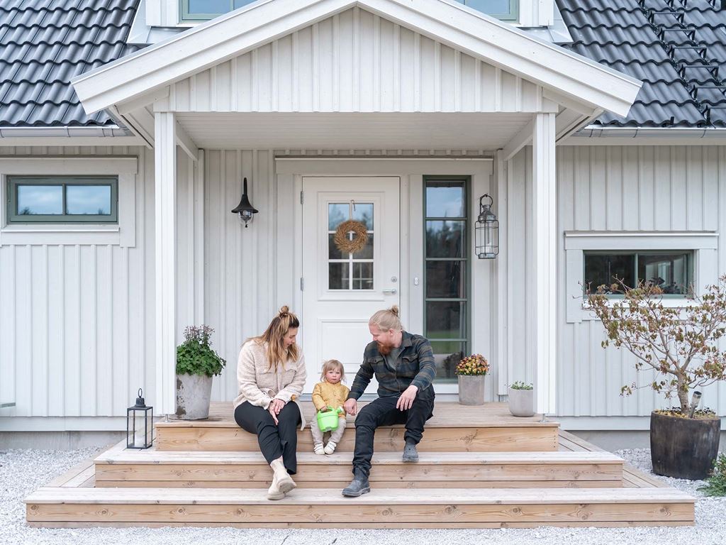 Familj på trappan till huset som de har byggt