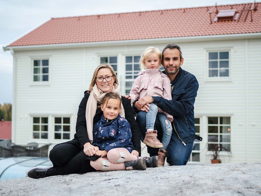 Familj med mamma, pappa och barn framför hus som de byggt med SmålandsVillan