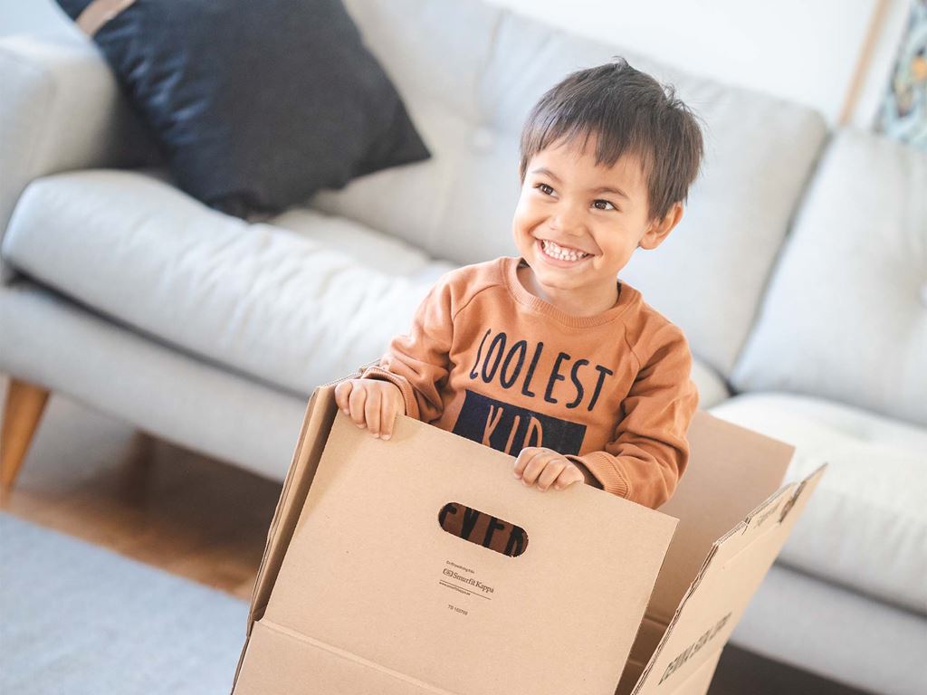 Barn leker i flyttkartong medans föräldrarna bygger nytt hus