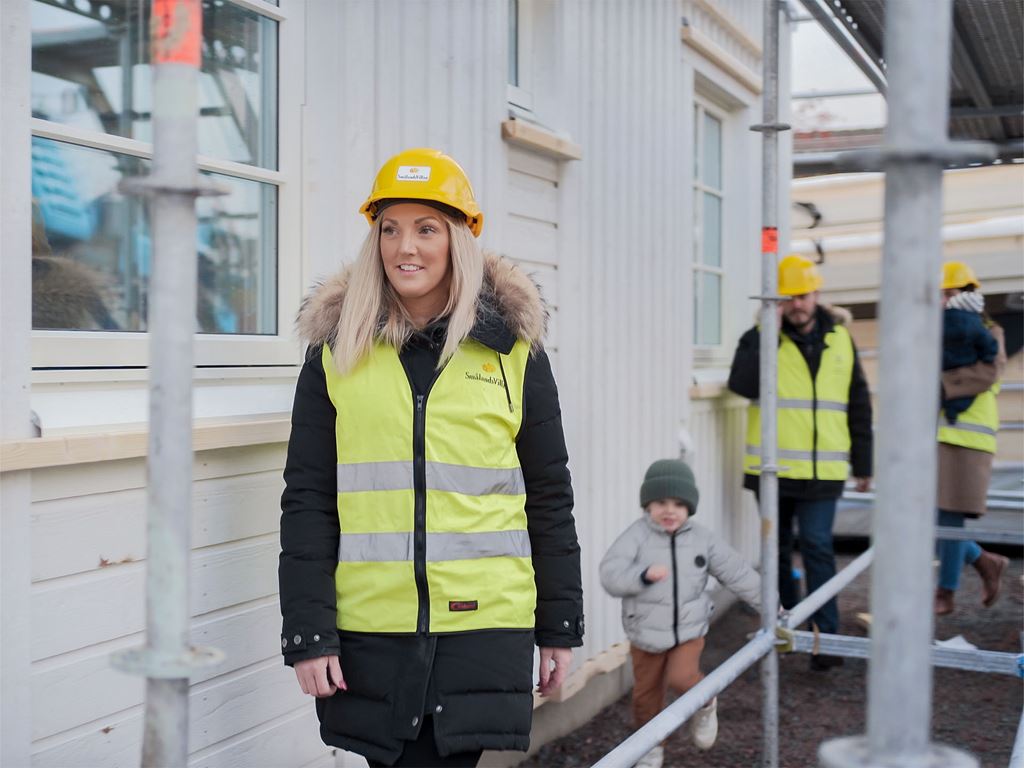 Kvinnlig säljare guidar kunder som håller på att bygga hus