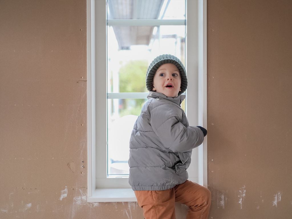 Förväntansfullt barn på inredningsbar övervåning i nybyggt hus