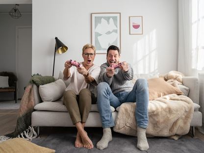 Äldre kvinna och man leke i soffan i nybyggt hus