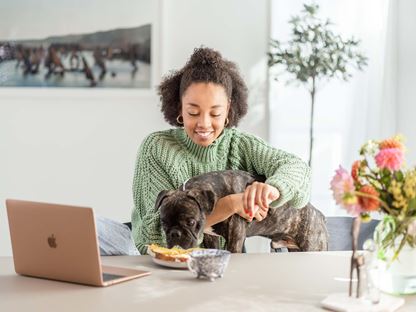 Kvinna äter frukost och jobbar hemifrån
