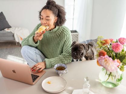 Kvinna tittar på laptop när hon äter frukost