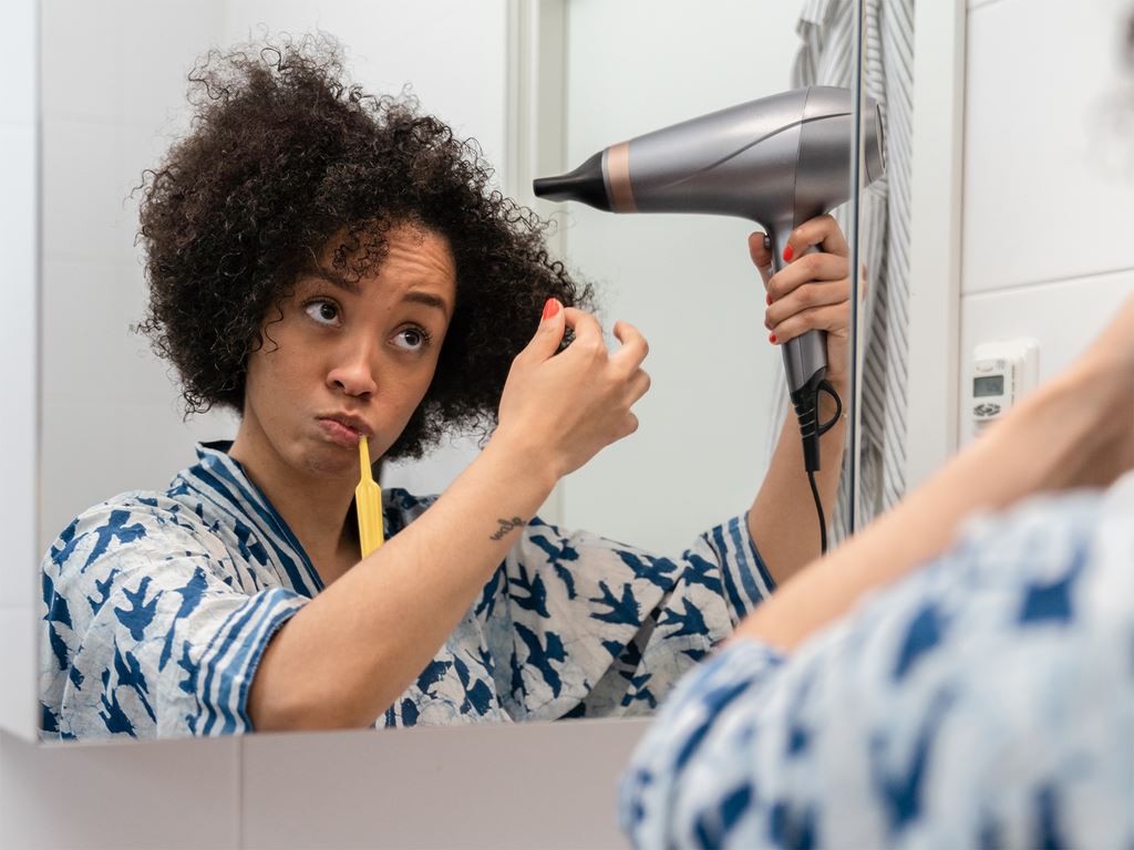 Kvinna fönar håret i badrum i nybyggt hus