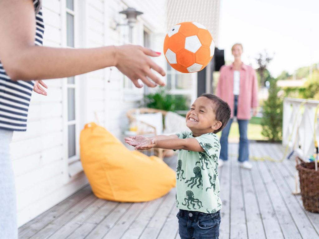 Barn leker med boll på altan