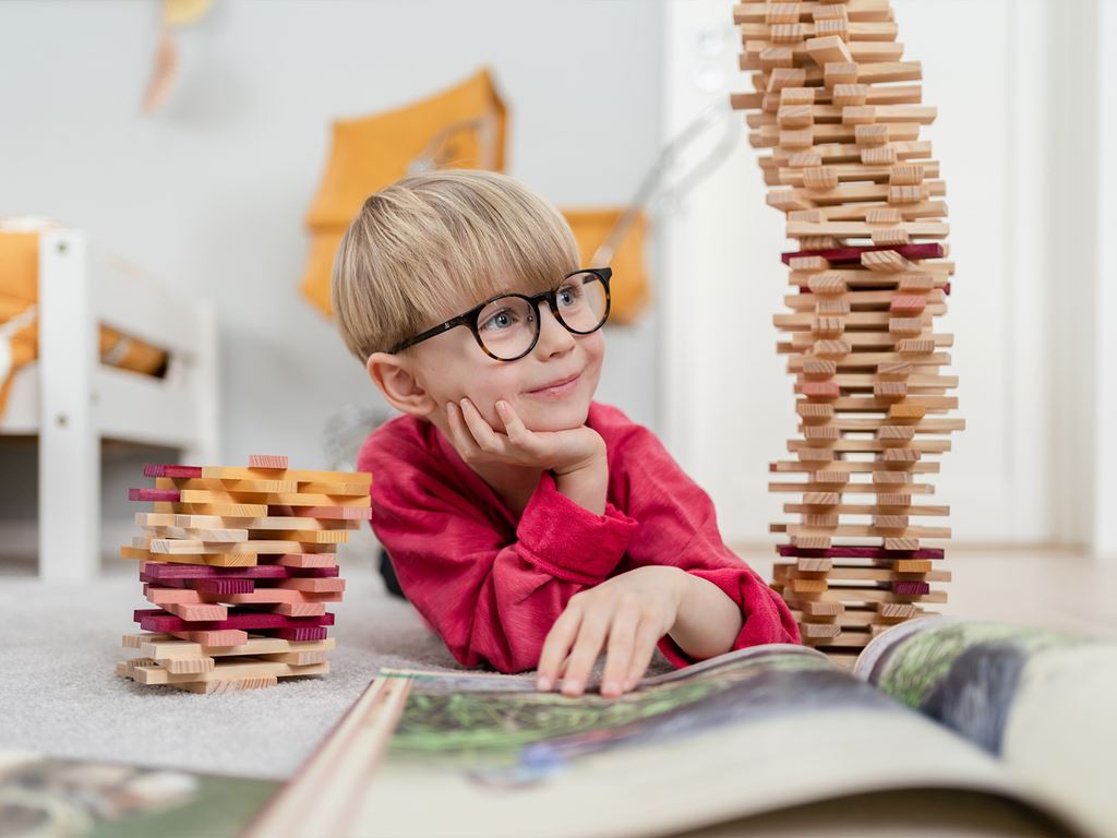 Pojke läs bok efter att ha byggt hus av klossar