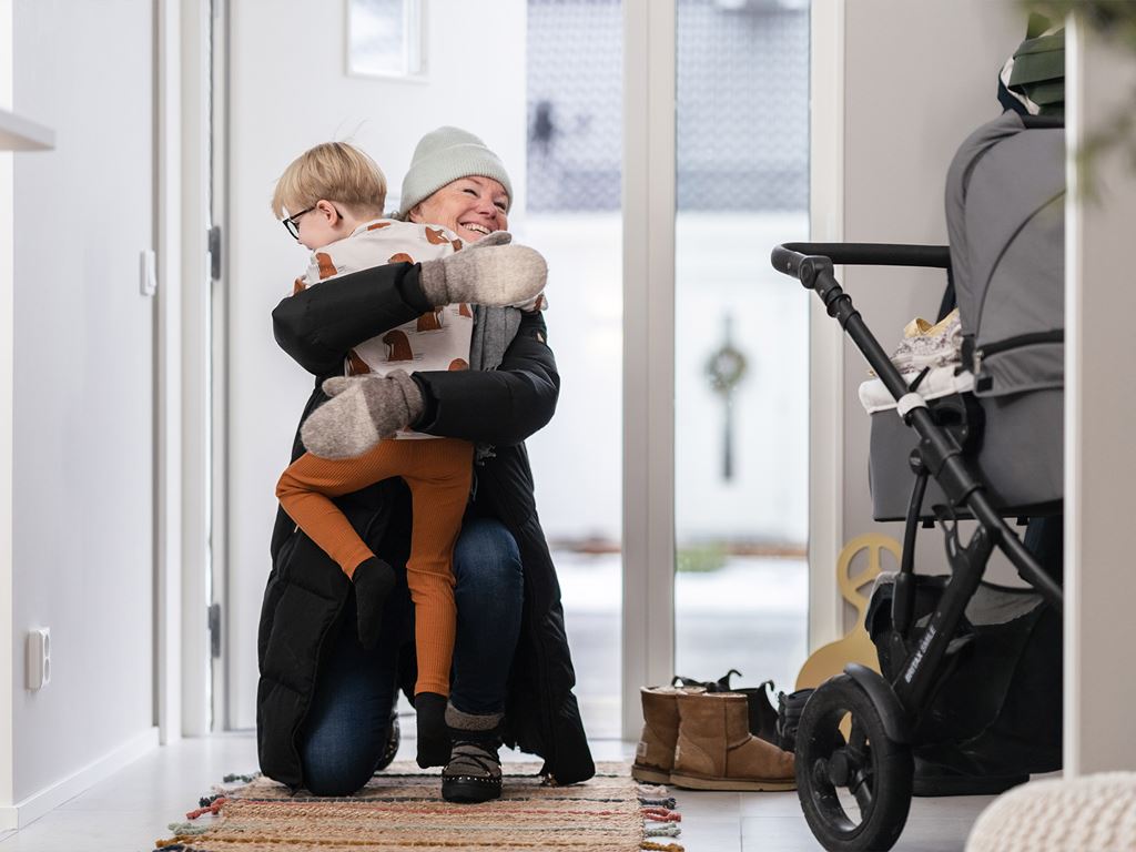 Äldre kvinna hälsar på barnbarn i nybyggt hus