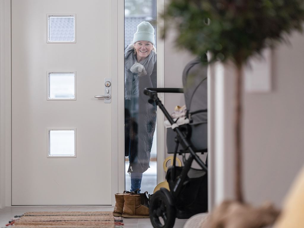 Äldre kvinna öppna dörren till enplanshus
