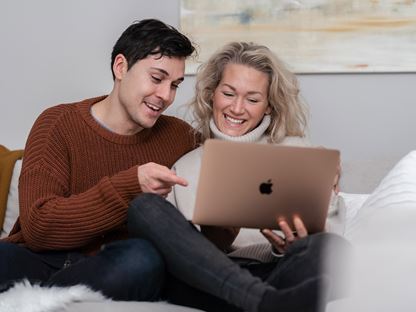 Ungt par läger artiklar på datorn om att bygga hus