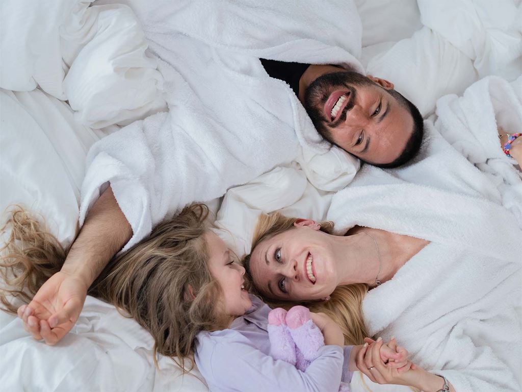 Man och kvinna kopplar av i säng på hotellrum